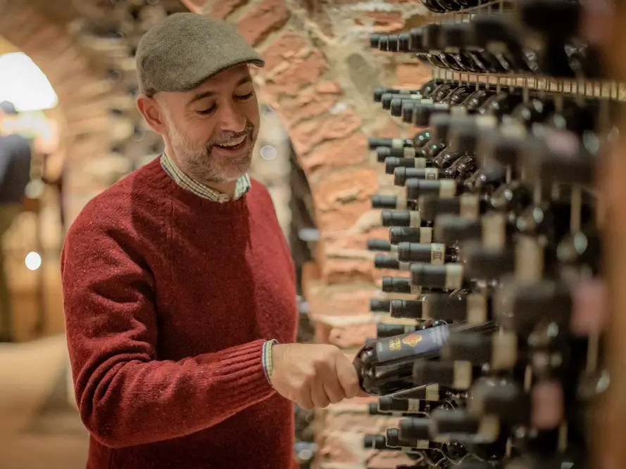 Croce di Febo wijnmaker Maurizio Comitini in de wijnkelder met flessen wijn uit de Montepulciano wijnregio in Toscane
